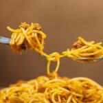 Piatto di pasta con verdure e condimento, simbolo di un'alimentazione quotidiana.