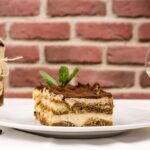 Tiramisù con crema al mascarpone, decorato con cacao e caffè, su un piatto elegante.