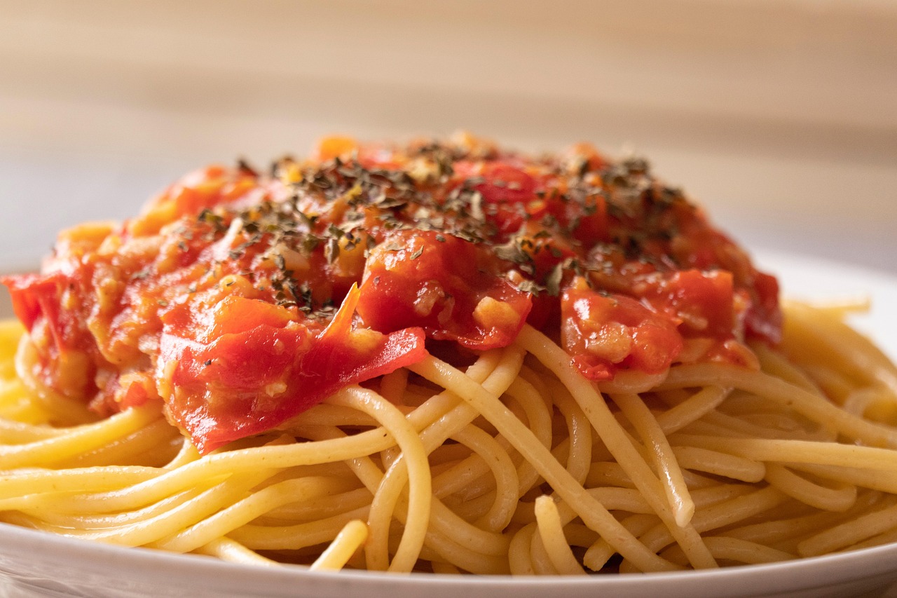 Pasta al pomodoro servita in un piatto, con pomodori freschi e basilico decorativo.